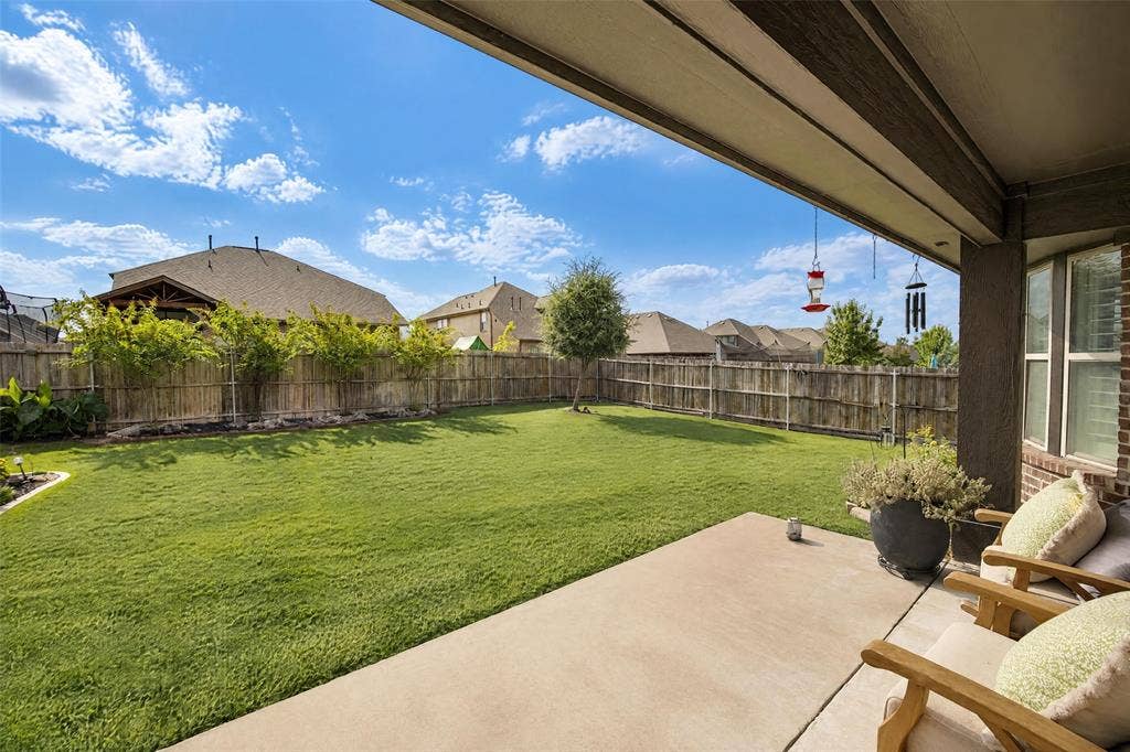 3210 Creekhaven Drive, Melissa, TX 75454 Covered concrete patio overlooking a private backyard featuring a manicured lawn, wooden perimeter fencing, and mature landscaping