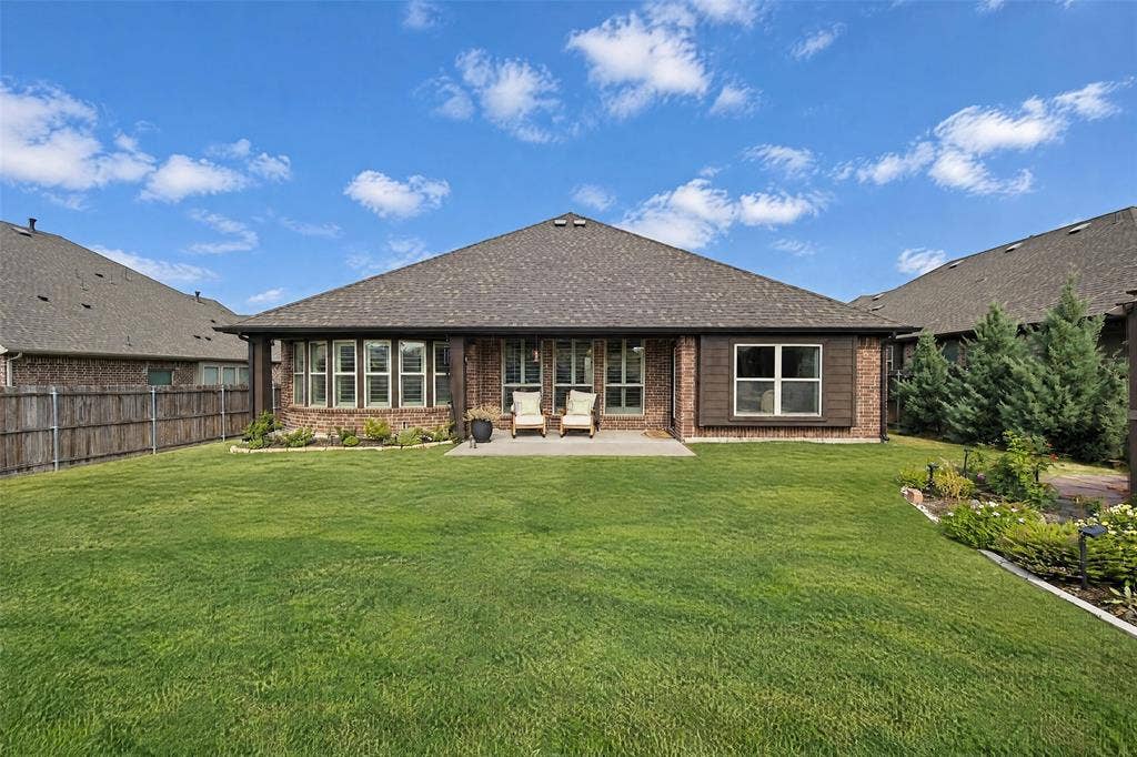 3210 Creekhaven Drive, Melissa, TX 75454 Brick exterior featuring a concrete patio, a deep-set roofline, multiple paneled windows, and a fully fenced backyard