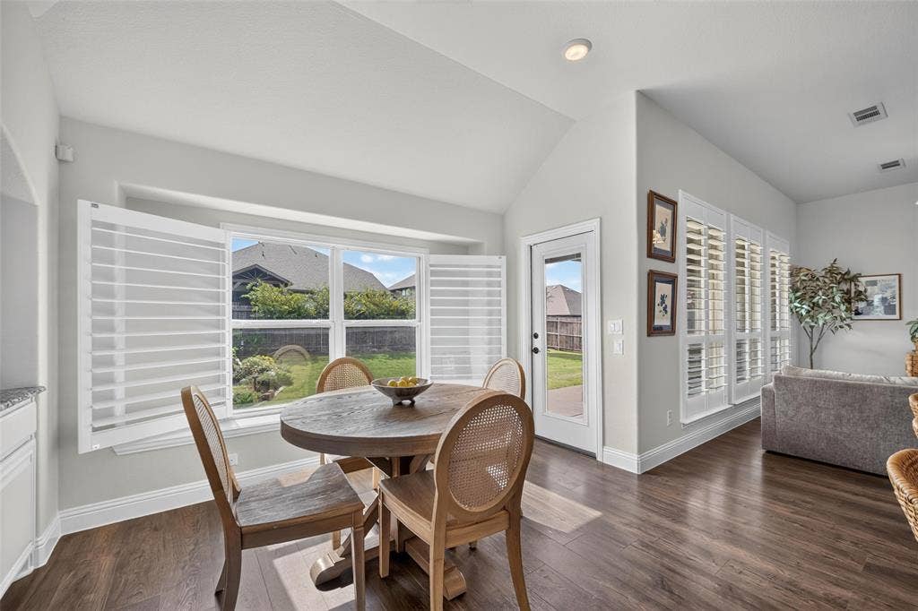 3210 Creekhaven Drive, Melissa, TX 75454 Vaulted ceiling featuring white shutters on expansive windows, wood-finish flooring, and a glass-paneled exterior door