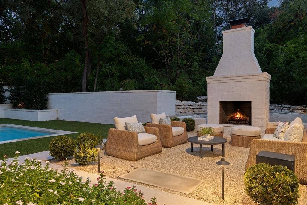 4201 Green Cliffs Road, Austin, TX 78746 Expansive outdoor living area featuring a prominent brick fireplace, a manicured lawn, and a swimming pool