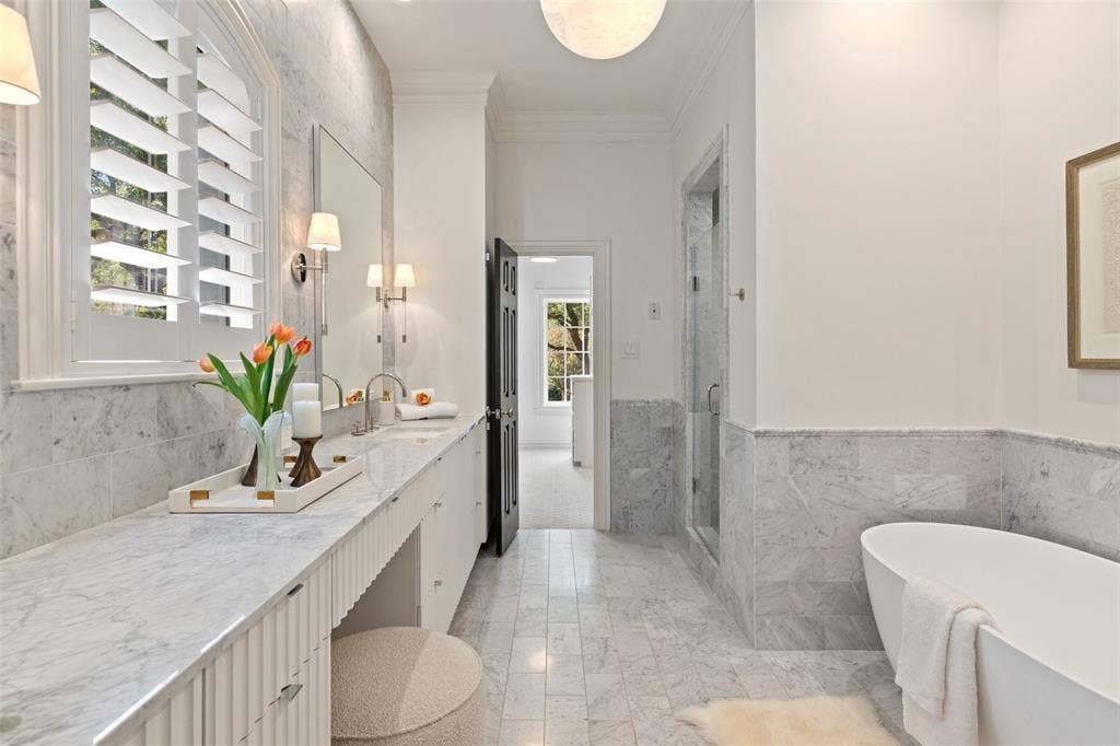 4201 Green Cliffs Road, Austin, TX 78746 Window with plantation shutters, double vanity with dual sinks, built-in bathtub, glass-enclosed shower, and stone tile flooring