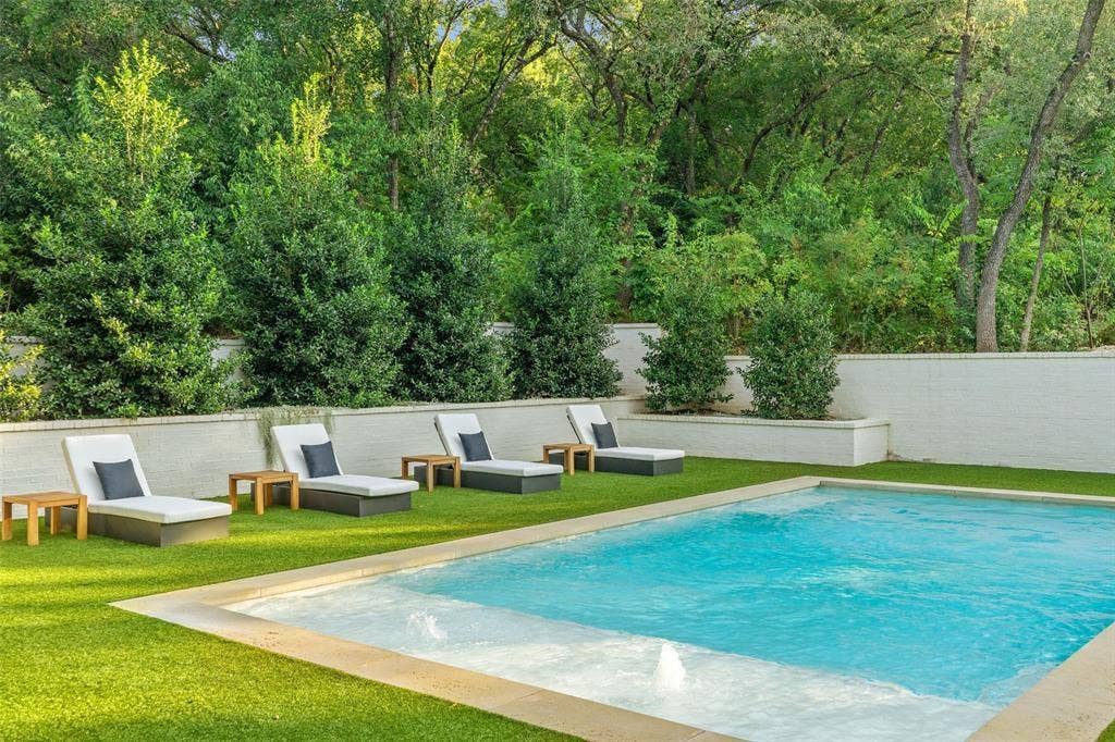 4201 Green Cliffs Road, Austin, TX 78746 Rectangular swimming pool with integrated spa, bordered by artificial turf and a white block wall