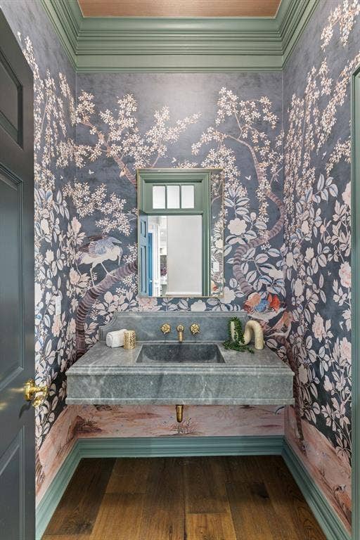 4201 Green Cliffs Road, Austin, TX 78746 Wood-finish flooring, ornate wall covering, vanity with integrated basin, polished brass fixtures, and a mirrored cabinet