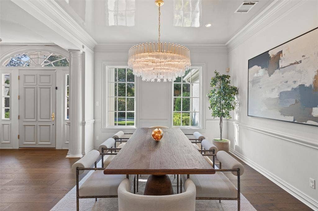 4201 Green Cliffs Road, Austin, TX 78746 Hardwood flooring, custom millwork, large windows, elegant chandelier, and a paneled entry door with transom window