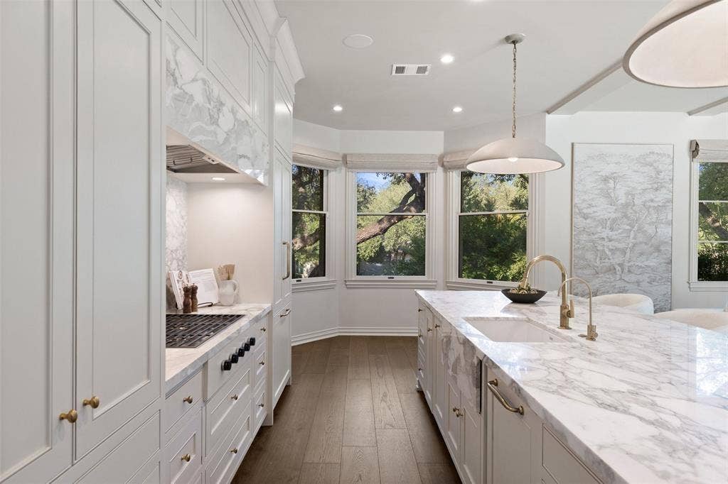 4201 Green Cliffs Road, Austin, TX 78746 White cabinetry with gold-finish hardware, built-in gas range, wood-finish flooring, white kitchen island with undermount sink, and recessed lighting