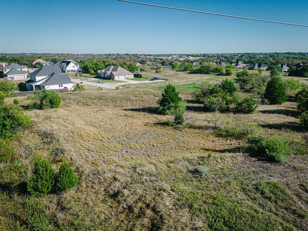 210 Caprock, Sunnyvale, TX 75182 Expansive undeveloped land with scattered mature trees and varied ground cover, bordered by established residential properties