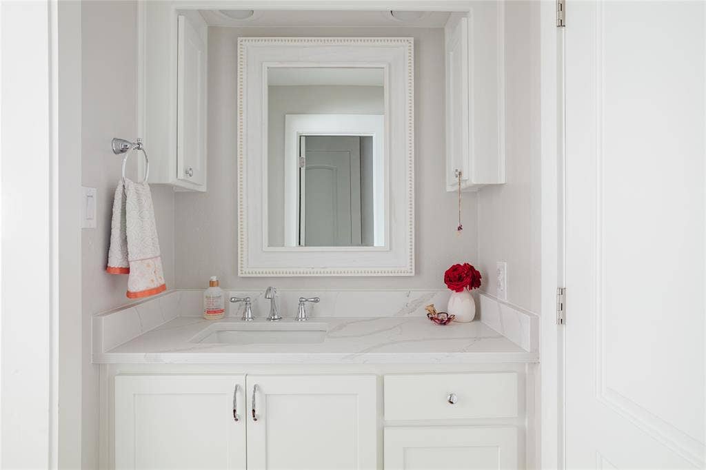 Spa-inspired custom bathroom vanity featuring a white cabinetry base with dual hardware pulls, a light-filled countertop with integrated sink, and polished chrome fixtures