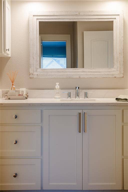 White shaker-style custom cabinetry with chrome hardware under a light-toned countertop