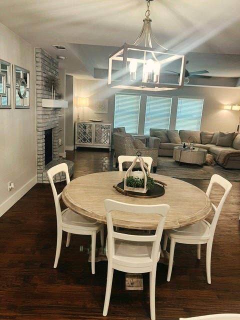 Open-concept living space with dark handscraped wood-finish flooring, a white brick fireplace, and a contemporary chandelier
