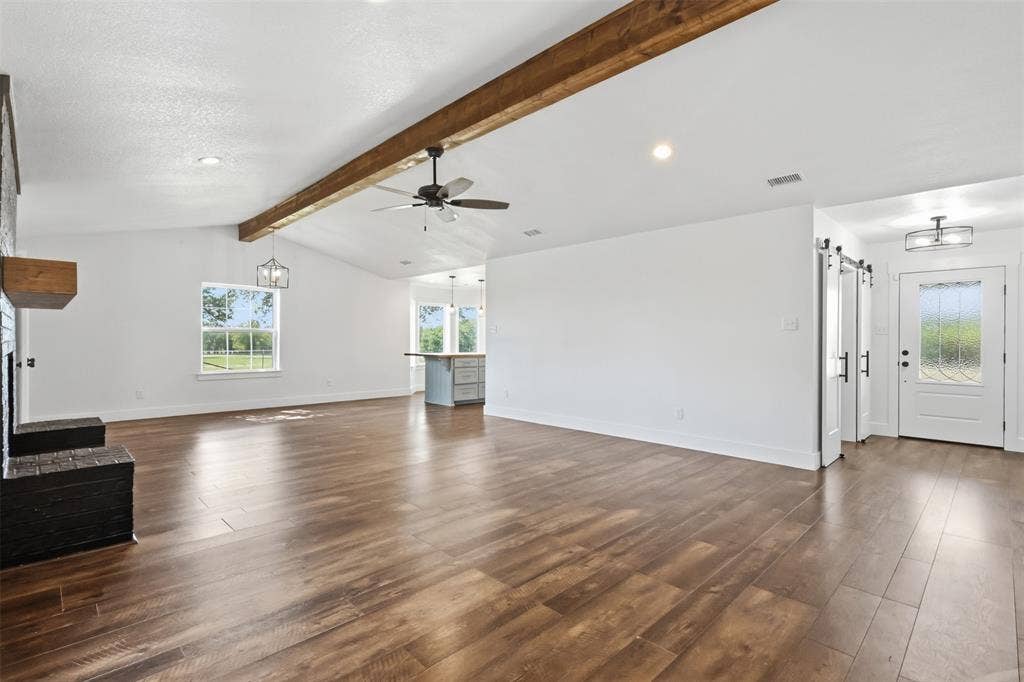Living room with dining space in front of window and kitchen to the back right.