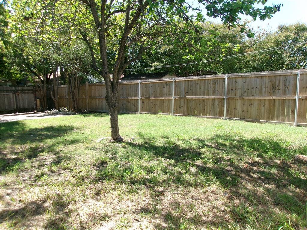 665 Stonewall Drive, Grand Prairie, TX 75052 Fenced yard with mature trees and a grass lawn