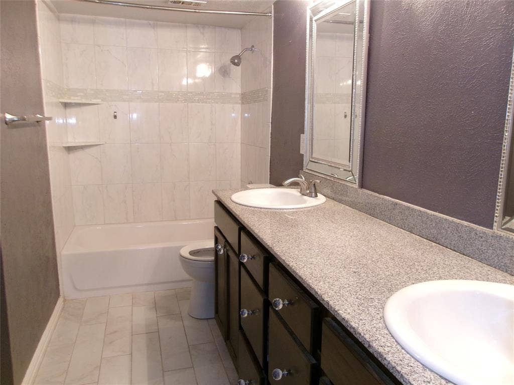 665 Stonewall Drive, Grand Prairie, TX 75052 Dual vanity with integrated sinks, dark wood-finish cabinetry, and light-toned speckled countertops
