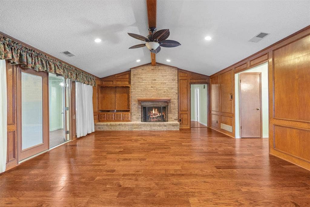 1305 Stonewood Drive, Carrollton, TX 75006 Spacious living room featuring elegant paneling and engineered wood flooring