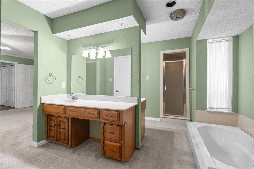 1305 Stonewood Drive, Carrollton, TX 75006 Primary bathroom has dual vanities, separate tub, and walk-in shower