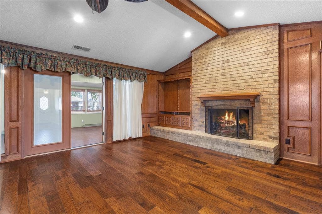 1305 Stonewood Drive, Carrollton, TX 75006 Gather around the brick fireplace in this spacious living room, featuring built-in cabinetry