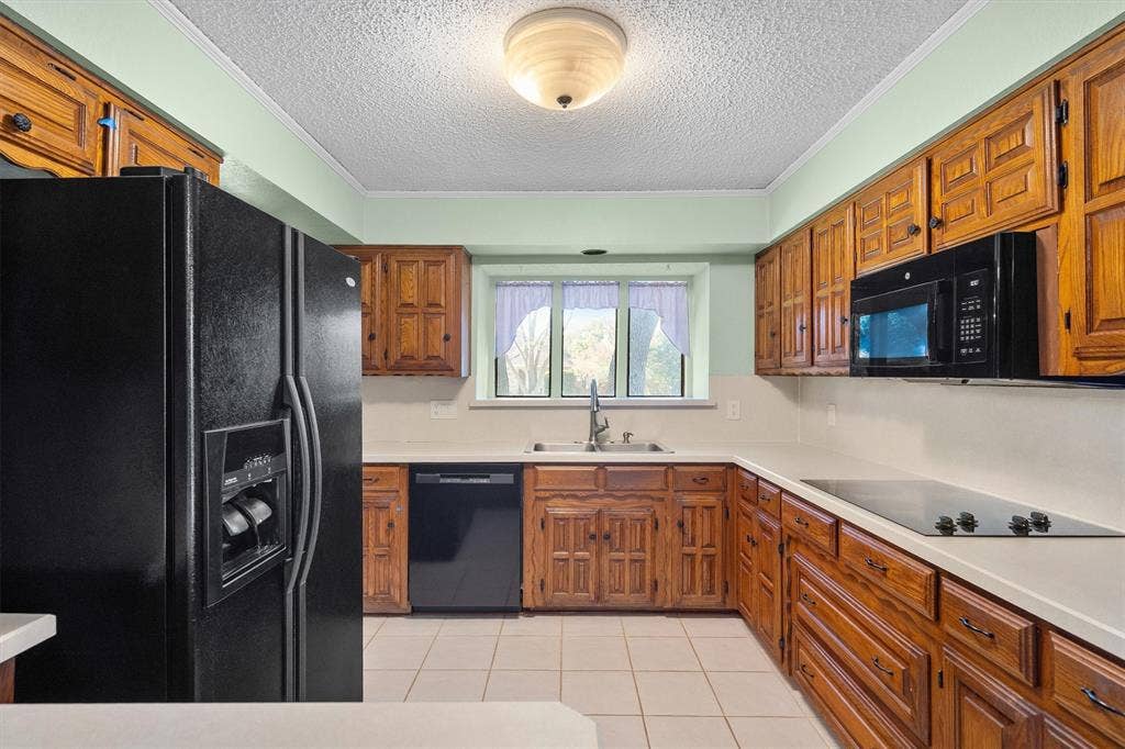 1305 Stonewood Drive, Carrollton, TX 75006 Functional kitchen featuring matching black appliances, cooktop, and generous cabinet storage