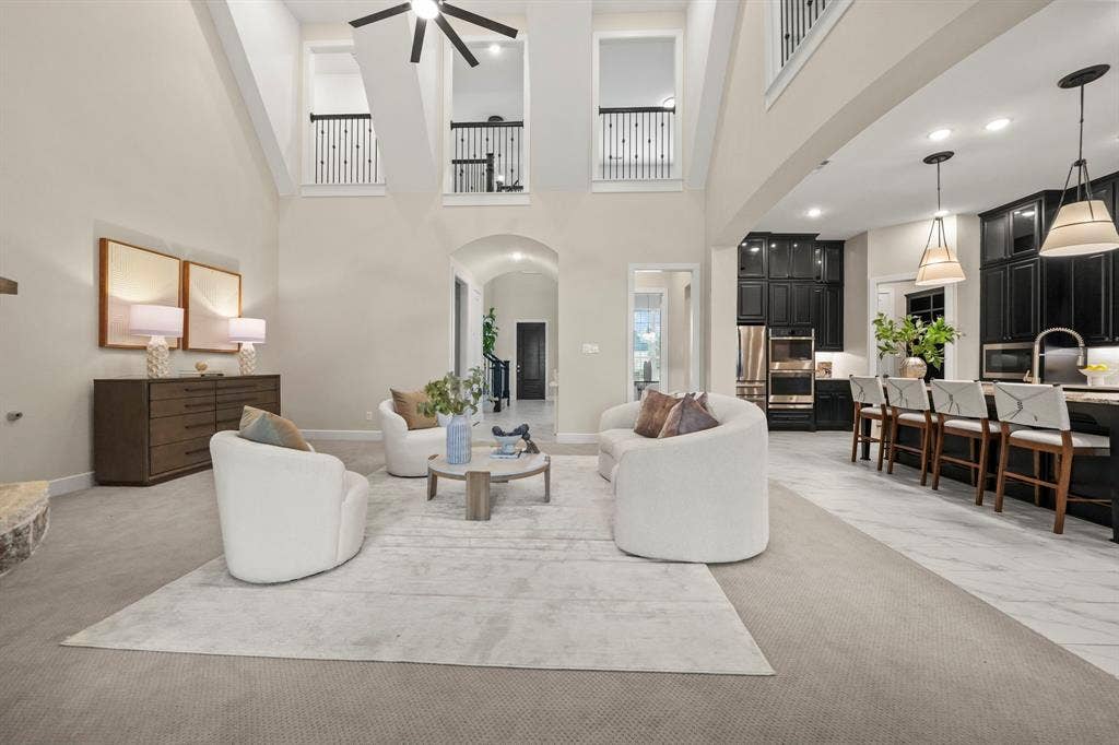 2628 Camden Court, Celina, TX 75009 Vaulted ceilings with architectural balcony overlook, tile flooring, recessed lighting, and custom dark cabinetry with pendant light fixtures