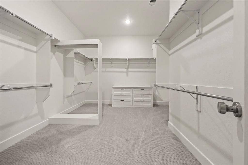 2628 Camden Court, Celina, TX 75009 Walk-in closet featuring tiered shelving, built-in drawer cabinetry, integrated hanging rods, and wall-to-wall carpeting