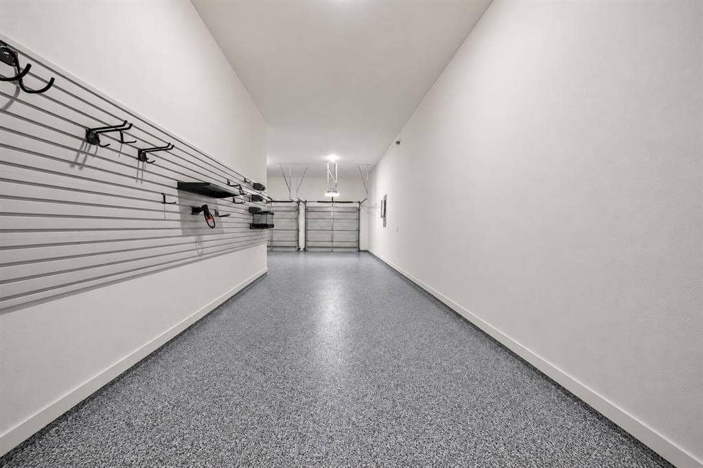 2628 Camden Court, Celina, TX 75009 Garage featuring epoxy-coated flooring, heavy-duty wall-mounted slat wall storage system, and dual metal roll-up doors