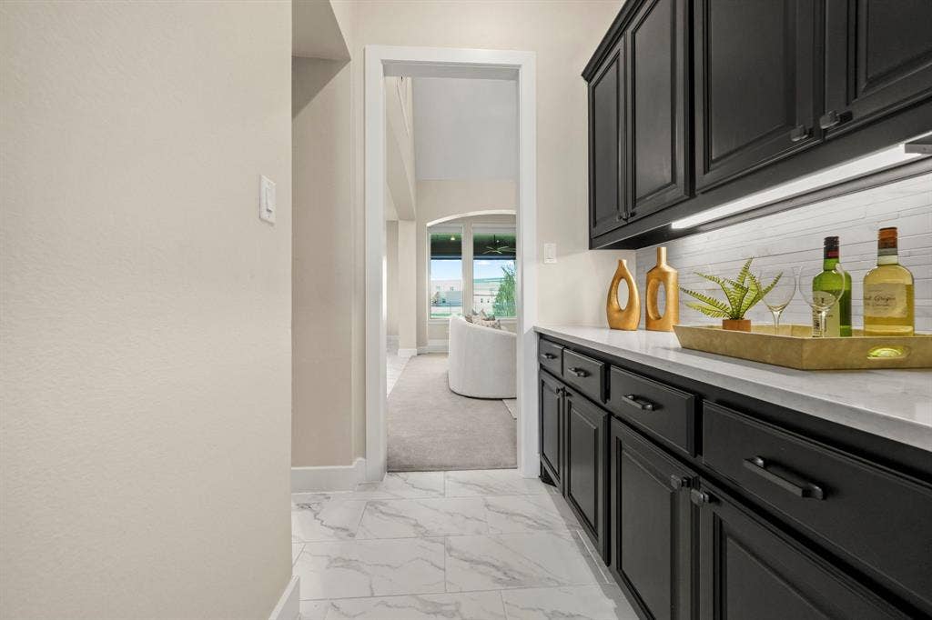 2628 Camden Court, Celina, TX 75009 Built-in cabinetry with matte black finish, light-toned stone-look countertop, horizontal tile backsplash, and light-toned tile flooring