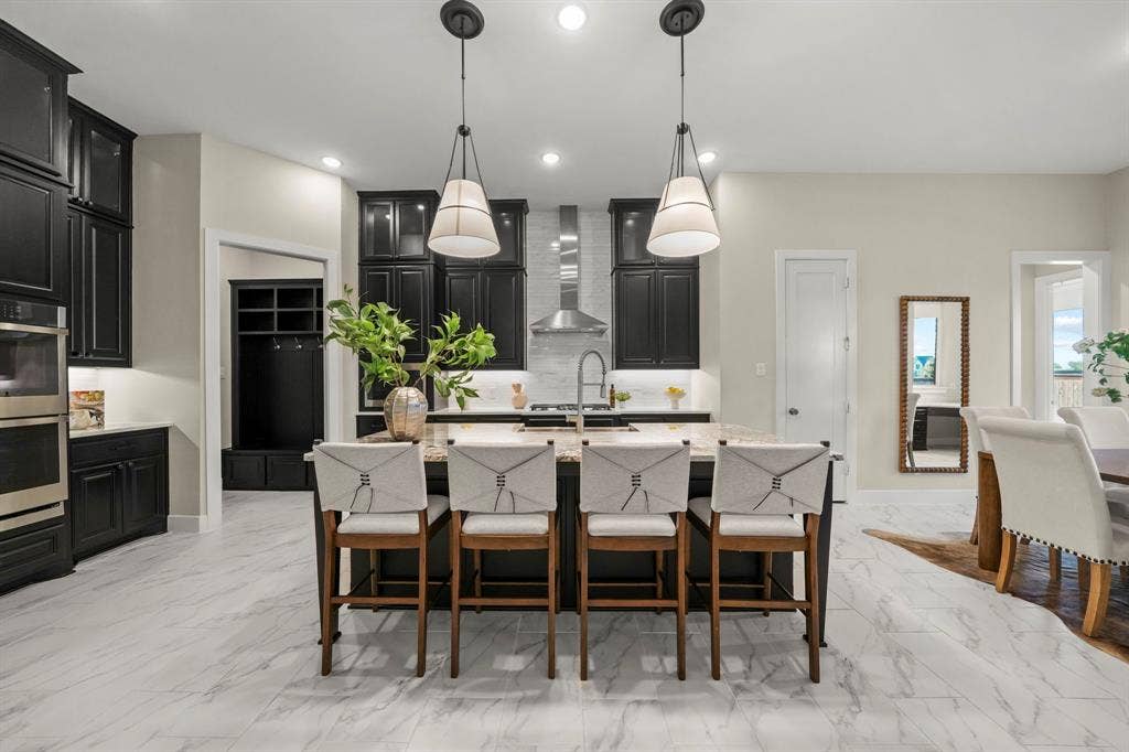 2628 Camden Court, Celina, TX 75009 Kitchen featuring custom cabinetry, stone-surface central island, stainless steel double wall oven, metal range hood, and tile flooring