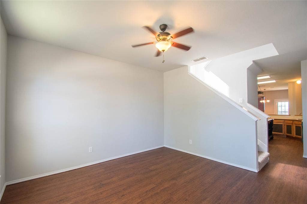 Wood-finish flooring, ceiling fan with integrated lighting, and a staircase with carpeted treads