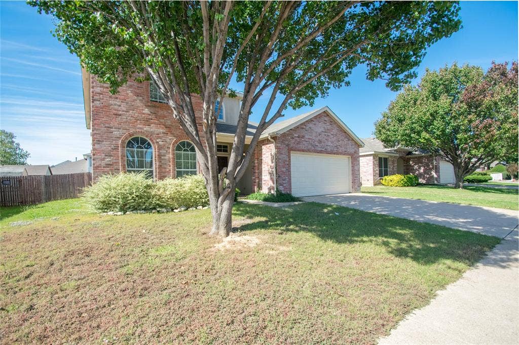 Brick exterior with arched windows, attached garage, and a concrete driveway