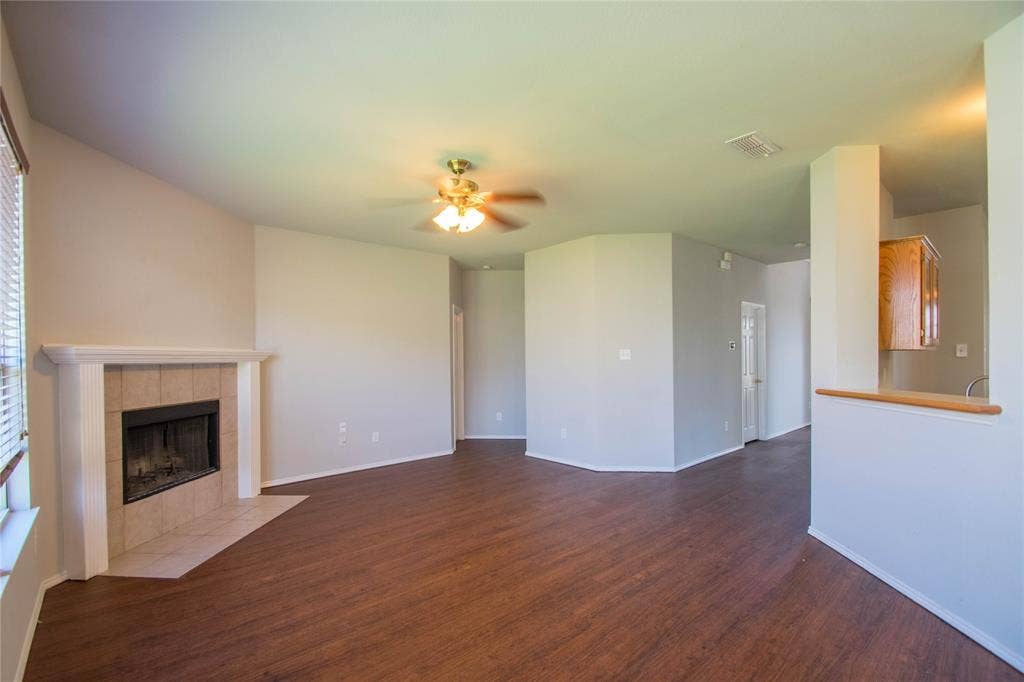 Wood-finish flooring throughout, vaulted ceiling, and a fireplace with a tile hearth and mantle
