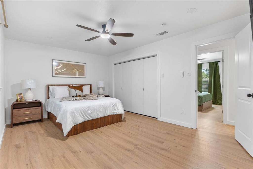 Wood-finish flooring, white walls, and a ceiling fan with integrated lighting
