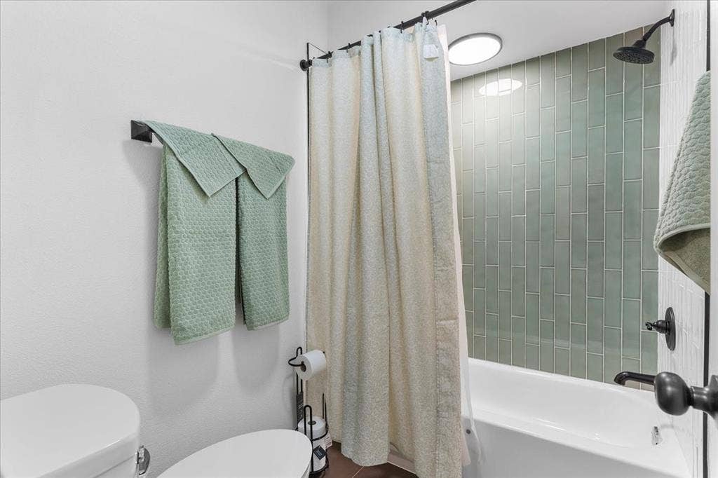 Built-in bathtub with subway tile surround, matte black shower head, and matte black fixtures