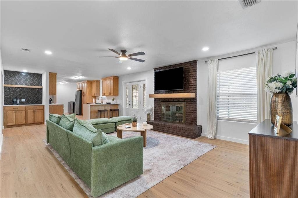 Living room featuring wood-finish flooring, a brick fireplace with a wood mantel, and recessed lighting
