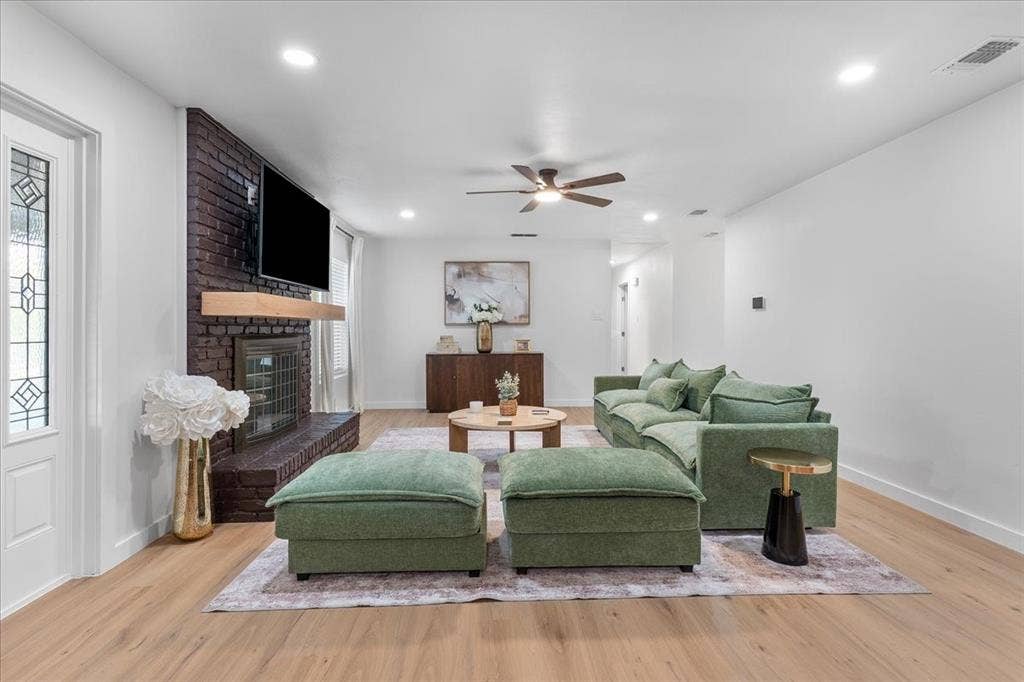 Wood-finish flooring, recessed lighting, and a dark brick fireplace with a wood mantel
