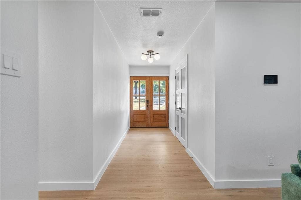 Light wood-finish flooring, white walls, and recessed lighting