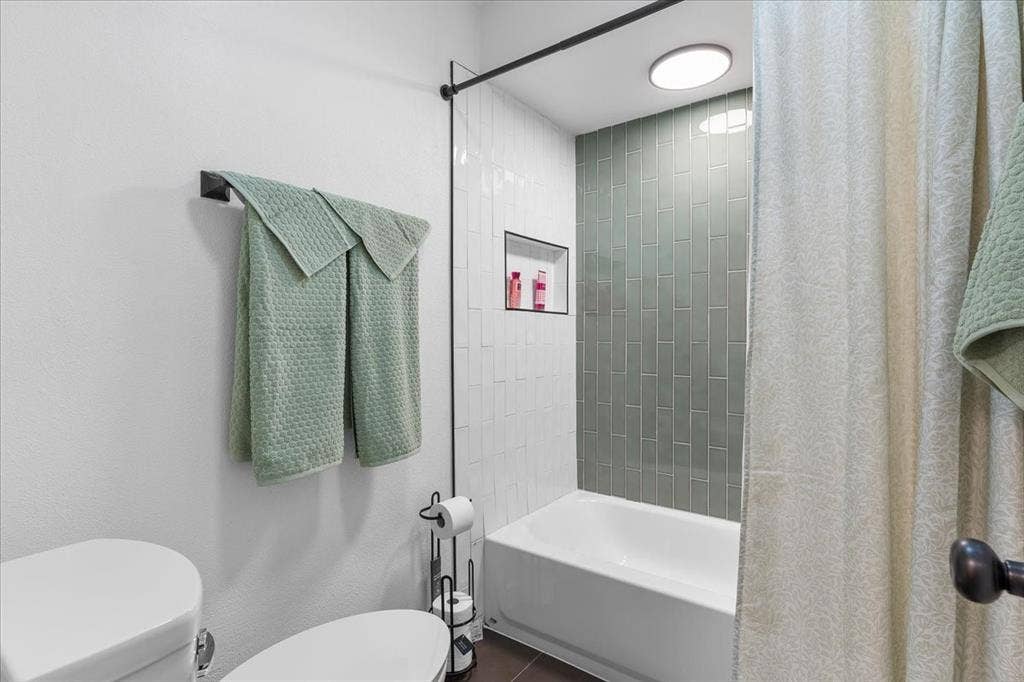 Bathtub with full-height subway tile surround, recessed niche, and integrated ceiling lighting