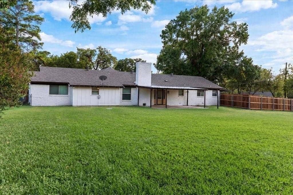 Expansive backyard with a covered patio, a privacy fence, and mature trees