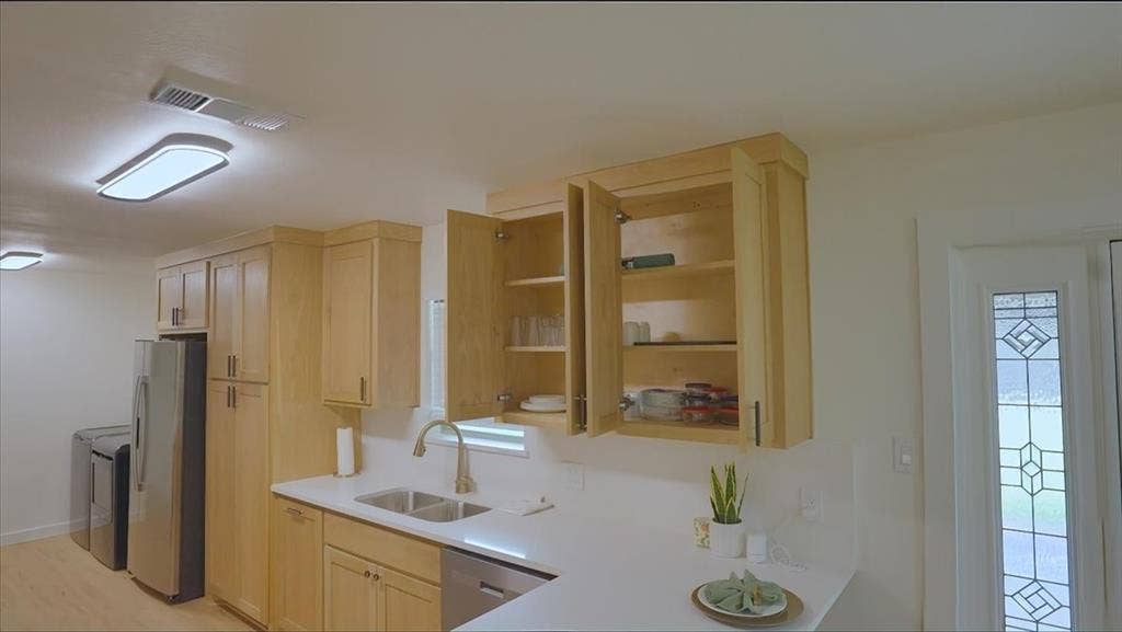 Light wood-finish cabinetry, stainless steel appliances, and a double basin sink