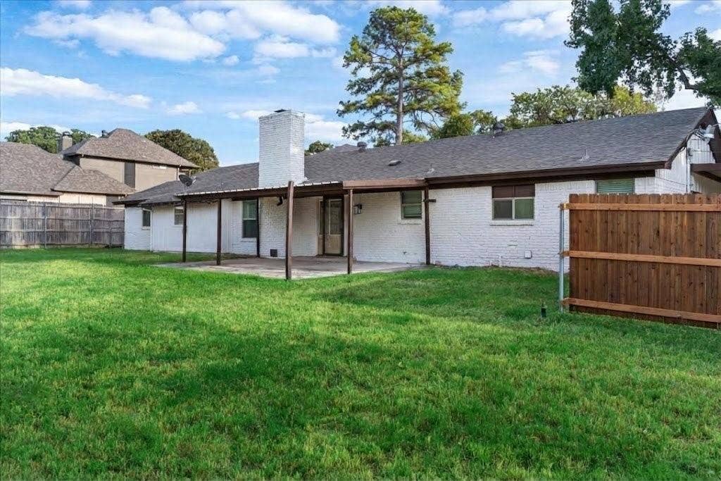 Expansive backyard featuring a manicured lawn, a covered patio, and a privacy fence