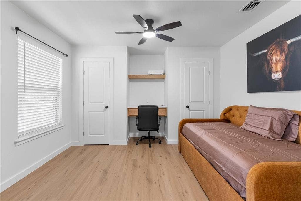 Great Flex room. Use as Bedroom or Office! Double Modern Doors, Recessed desk area with a wood-finish shelf, wood-finish flooring, and a ceiling fan with integrated lighting