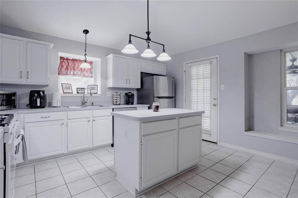 2918 Periwinkle Court, Garland, TX 75040 White cabinetry, tile flooring, central island, stainless steel refrigerator, and recessed window