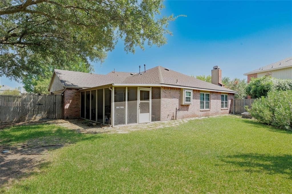 2918 Periwinkle Court, Garland, TX 75040 Expansive backyard featuring a screened porch, brick exterior, and a wood privacy fence