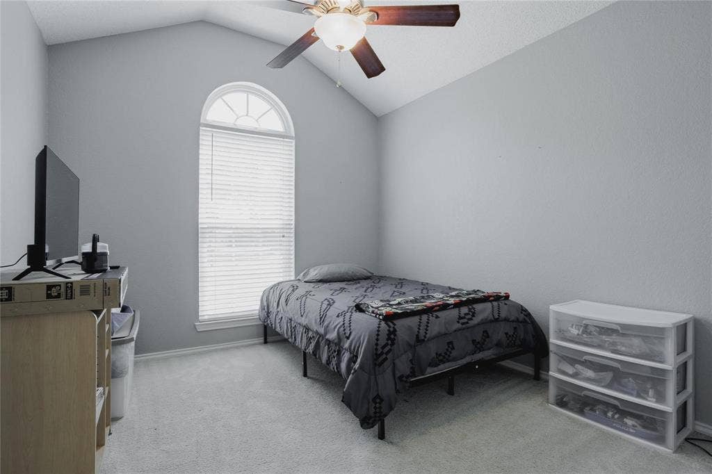 2918 Periwinkle Court, Garland, TX 75040 Vaulted ceiling with ceiling fan, arched window with horizontal blinds, neutral wall paint, and carpet flooring