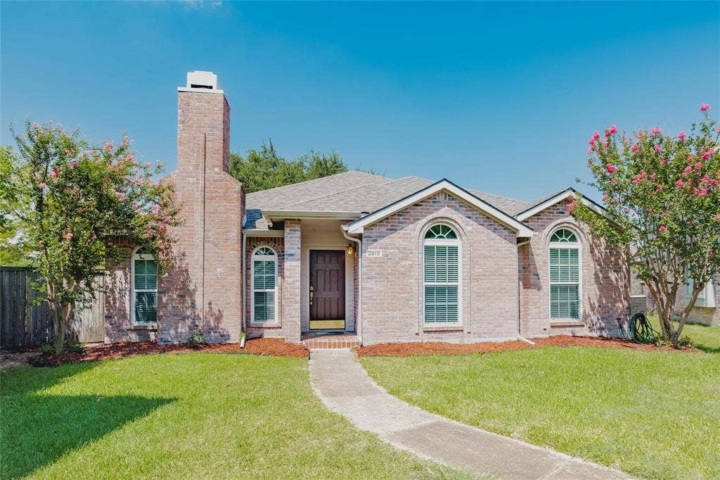 2918 Periwinkle Court, Garland, TX 75040 Brick exterior with arched windows, a prominent brick chimney, and a covered entry