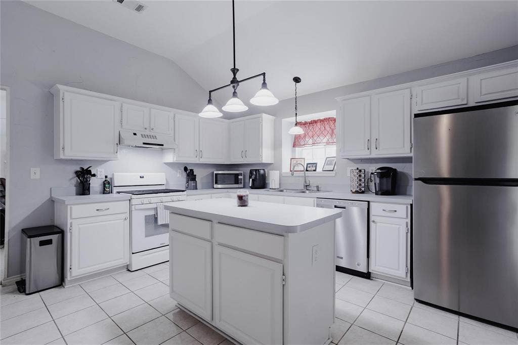 2918 Periwinkle Court, Garland, TX 75040 Spacious kitchen featuring white cabinetry, light-toned countertops, and a central island
