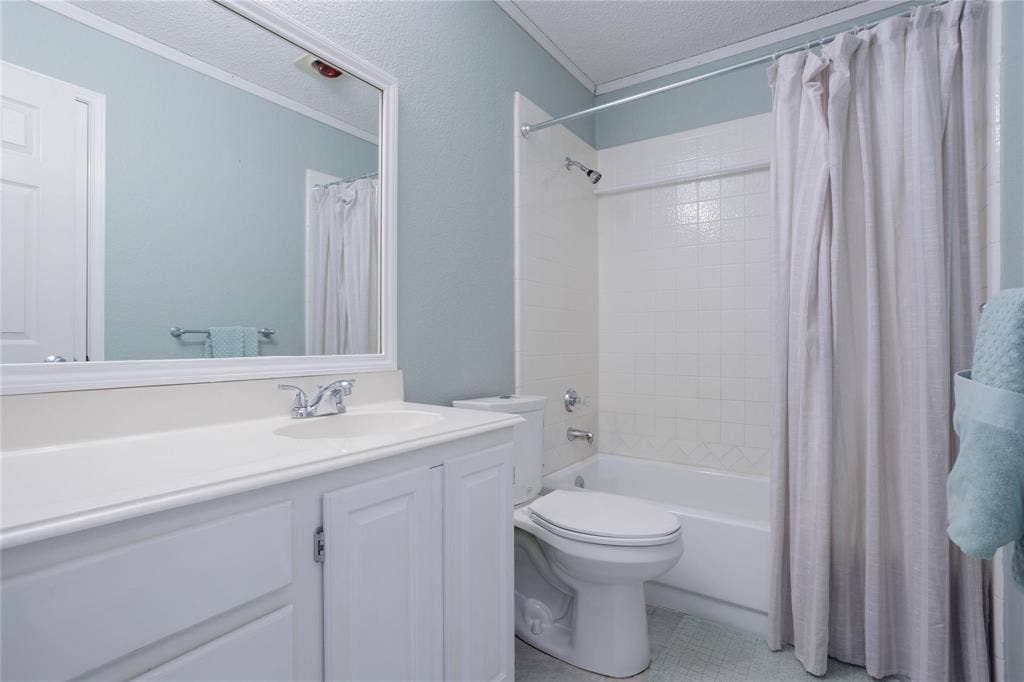 2918 Periwinkle Court, Garland, TX 75040 White vanity with integrated sink, chrome faucet, framed mirror, and a shower-over-tub combination with white tile surround