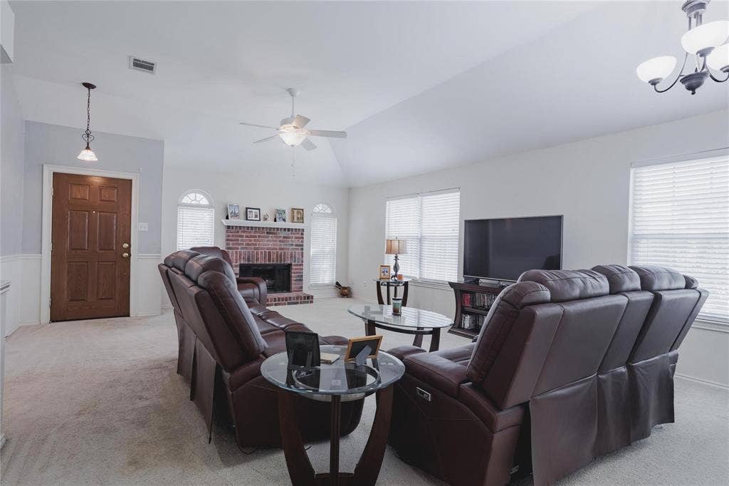 2918 Periwinkle Court, Garland, TX 75040 Vaulted ceiling with ceiling fan, brick fireplace, arched windows, and a panel front door