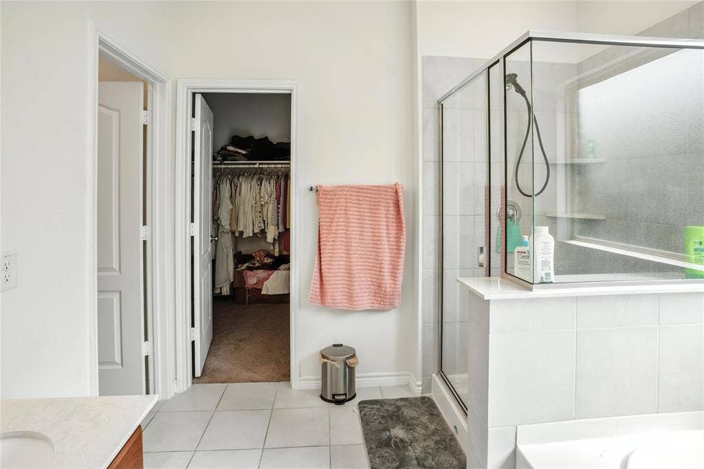 Bathroom featuring vanity, a shower stall, a walk in closet, tile patterned floors, and a bathtub