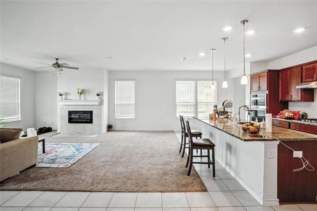 Kitchen with dark brown cabinets, dark stone countertops, a fireplace, open floor plan, and a kitchen breakfast bar
