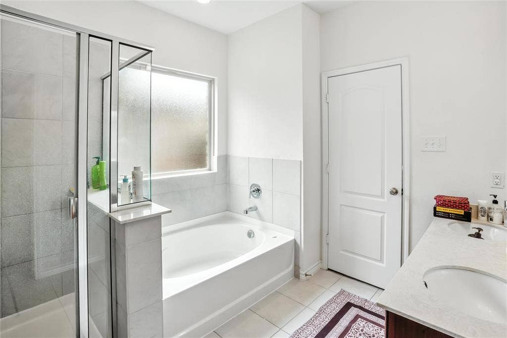 Full bathroom featuring a bath, a stall shower, tile patterned flooring, and double vanity