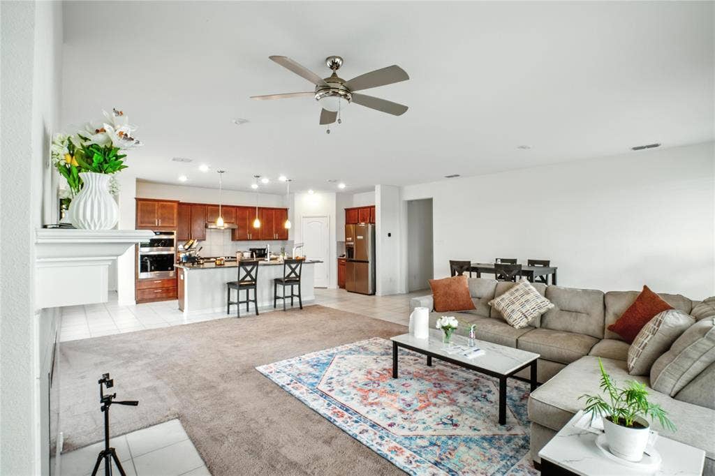Living room with light tile patterned floors, recessed lighting, light carpet, and a ceiling fan