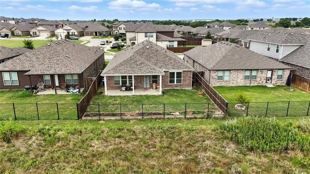 Back of house featuring a patio, a residential view, brick siding, and a fenced backyard